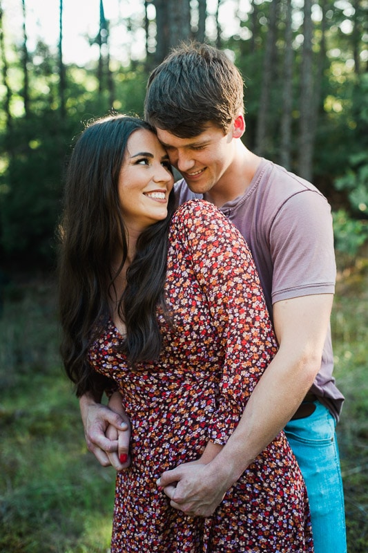 Couple embracing each other in wooded field. Photo by Arkansas Wedding Collection.