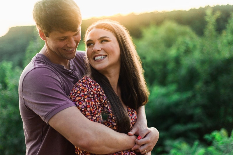Couple laughing while man holds her in a hug from behind for Petit Jean Wedding Engagement session. Photo by Arkansas Wedding Collection.