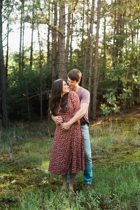 Couple embracing each other in wooded field. Photo by Arkansas Wedding Collection.