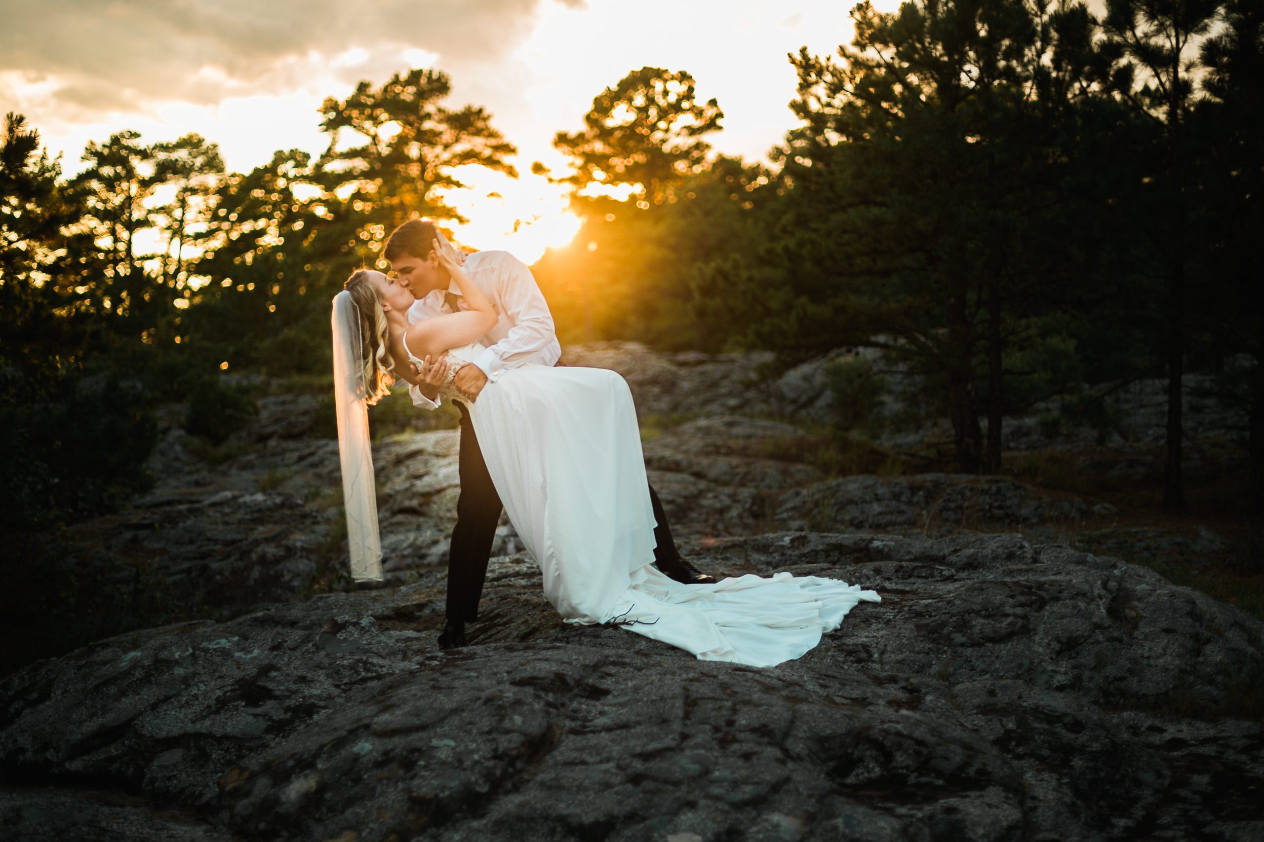 groom dipping his bride at sunset at Petit Jean State Park