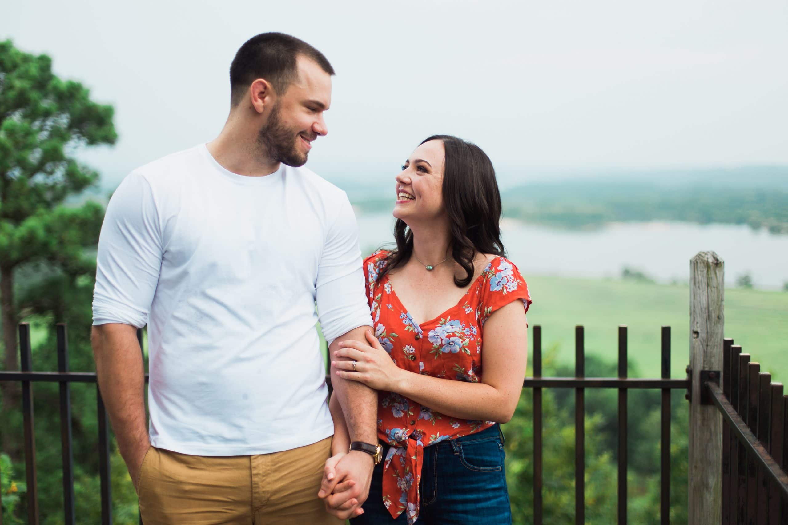 couple-smiling-at-each-other-and-holding-hands-at-mountain-overlook