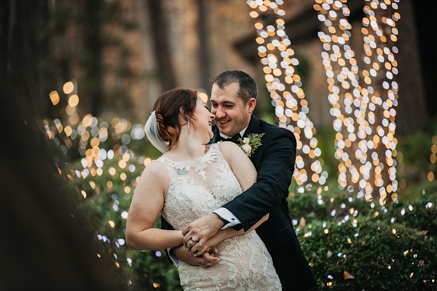 bride-and-groom-holding-each-other-in-front-of-white-christmas-lights-at-garvan-woodland-gardens