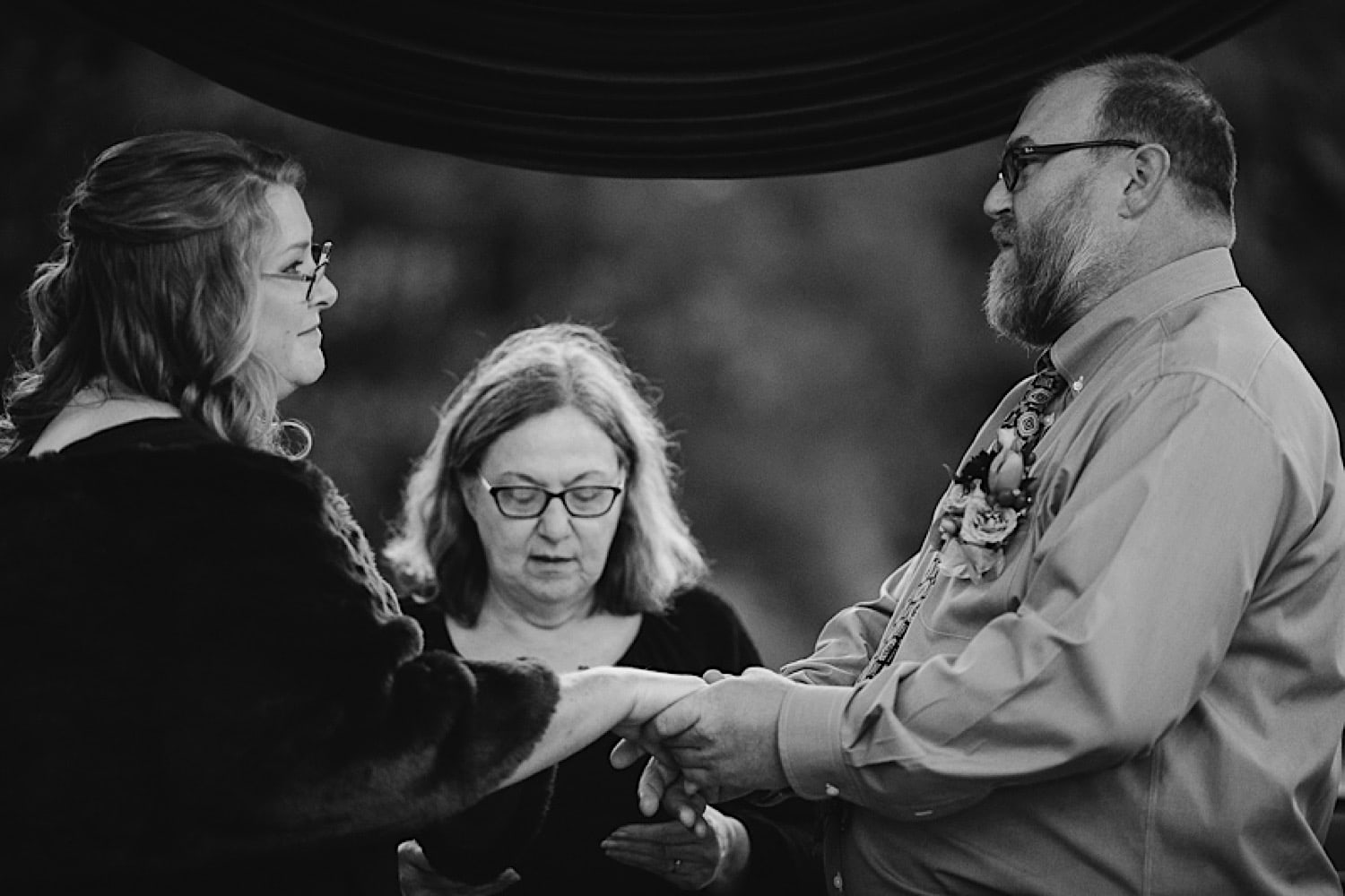 Bride and groom holding hands at ceremony with Margot Elliot as officiant