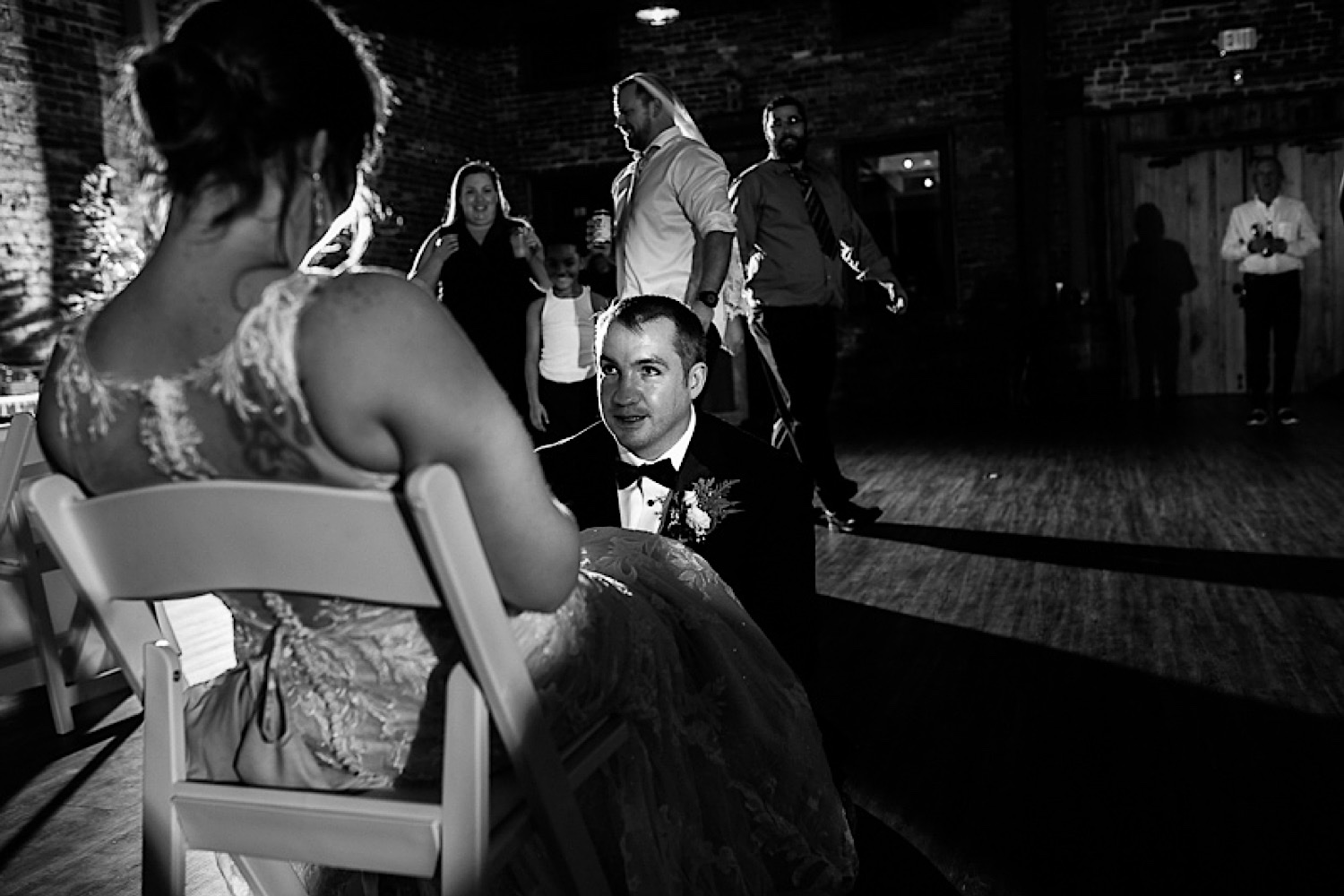 groom-getting-garter-at-bride-sitting-in-chair